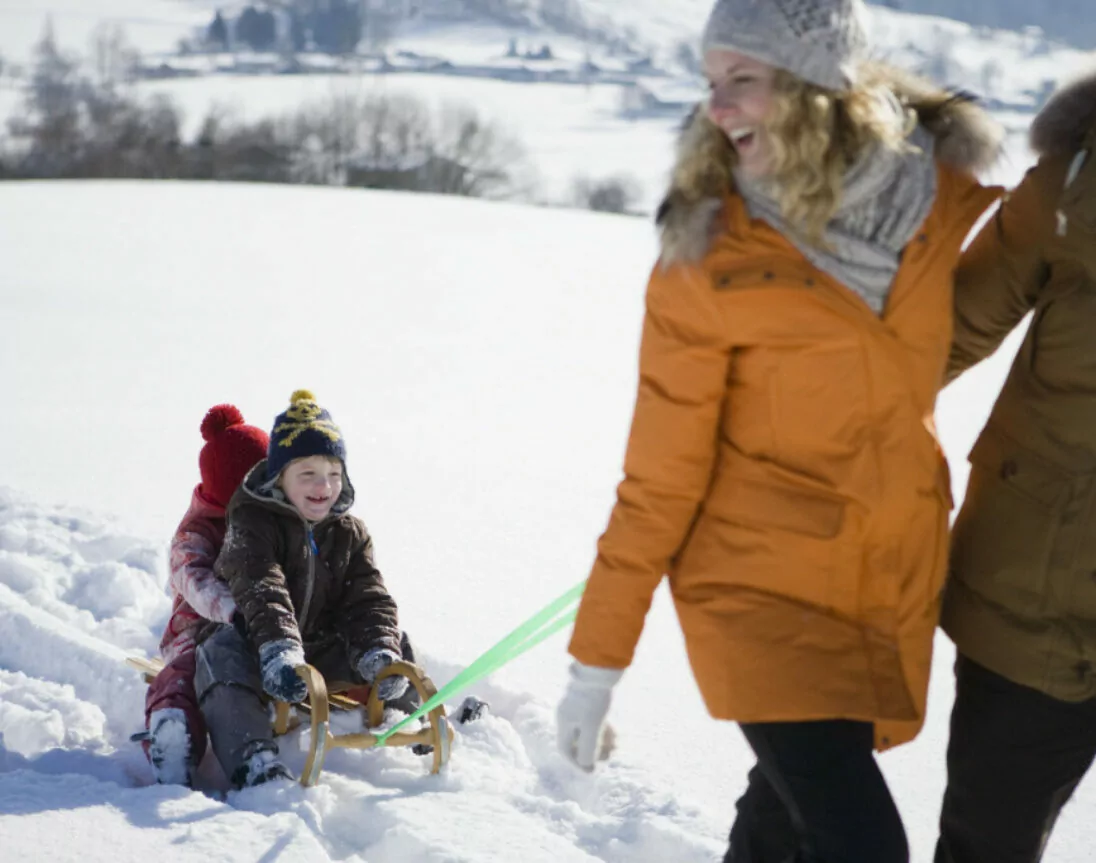 Un homme et une femme tirant des enfants sur une luge